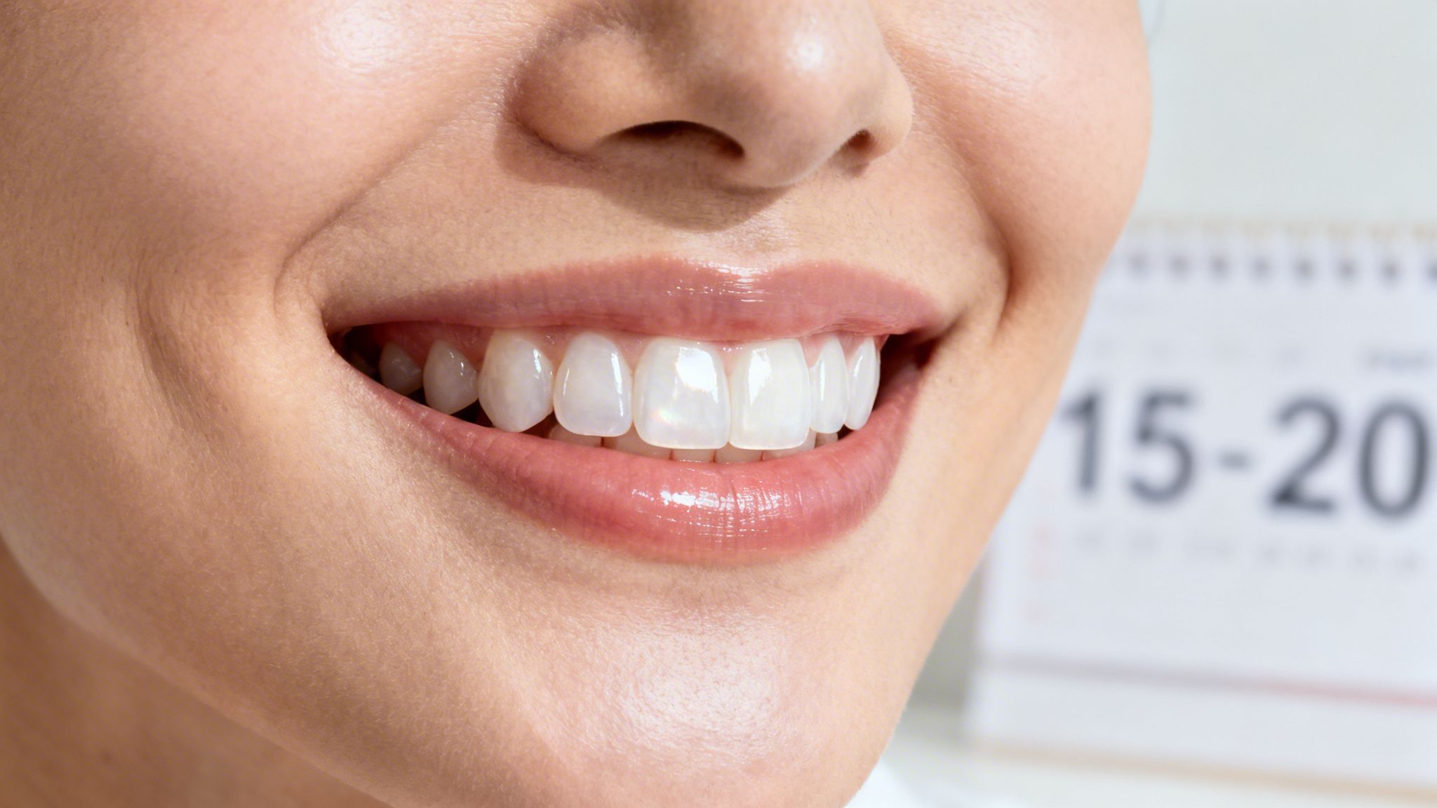 Close-up of a smiling person revealing healthy, gleaming white teeth and glossy lips.