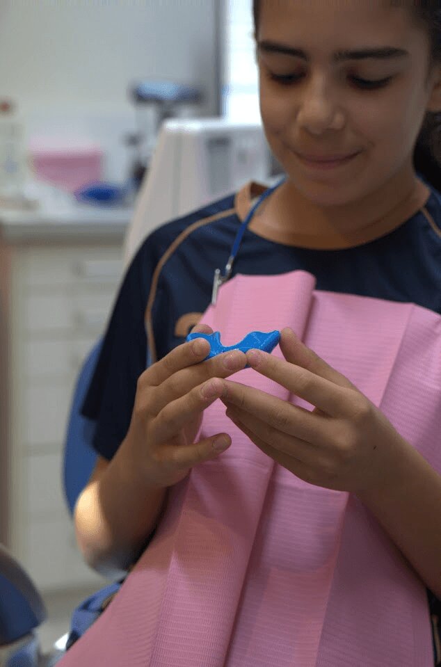 Young patient holding a custom mouthguard at The Smile Spot