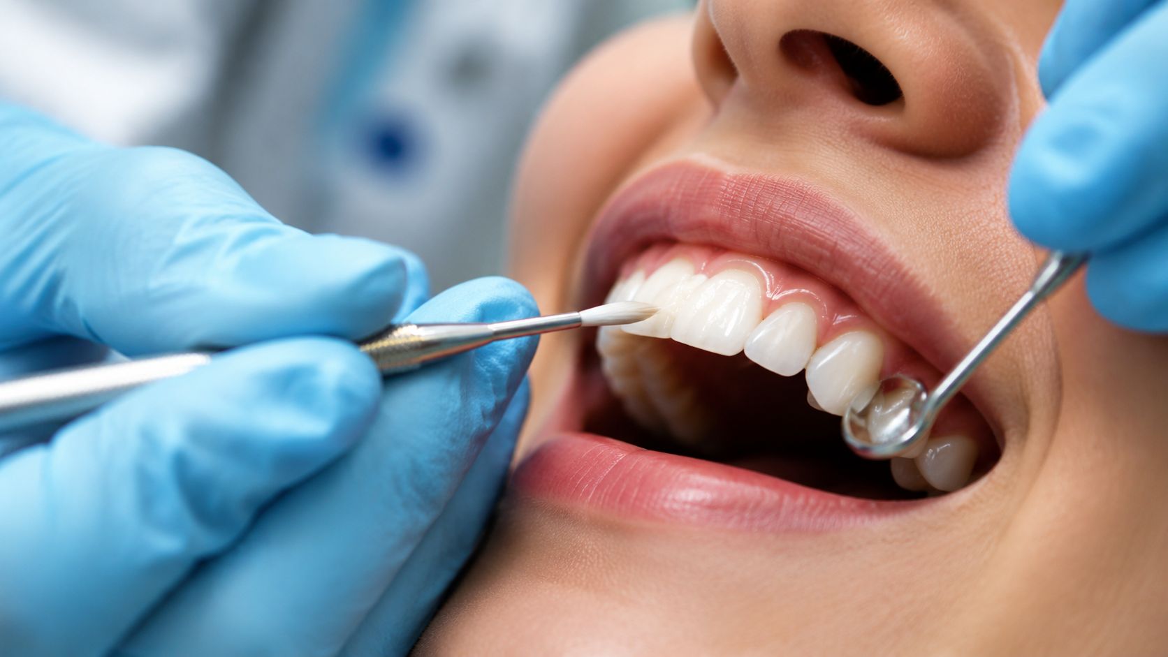 A dentist wearing blue surgical gloves performing a dental procedure on a patient in a clinic.