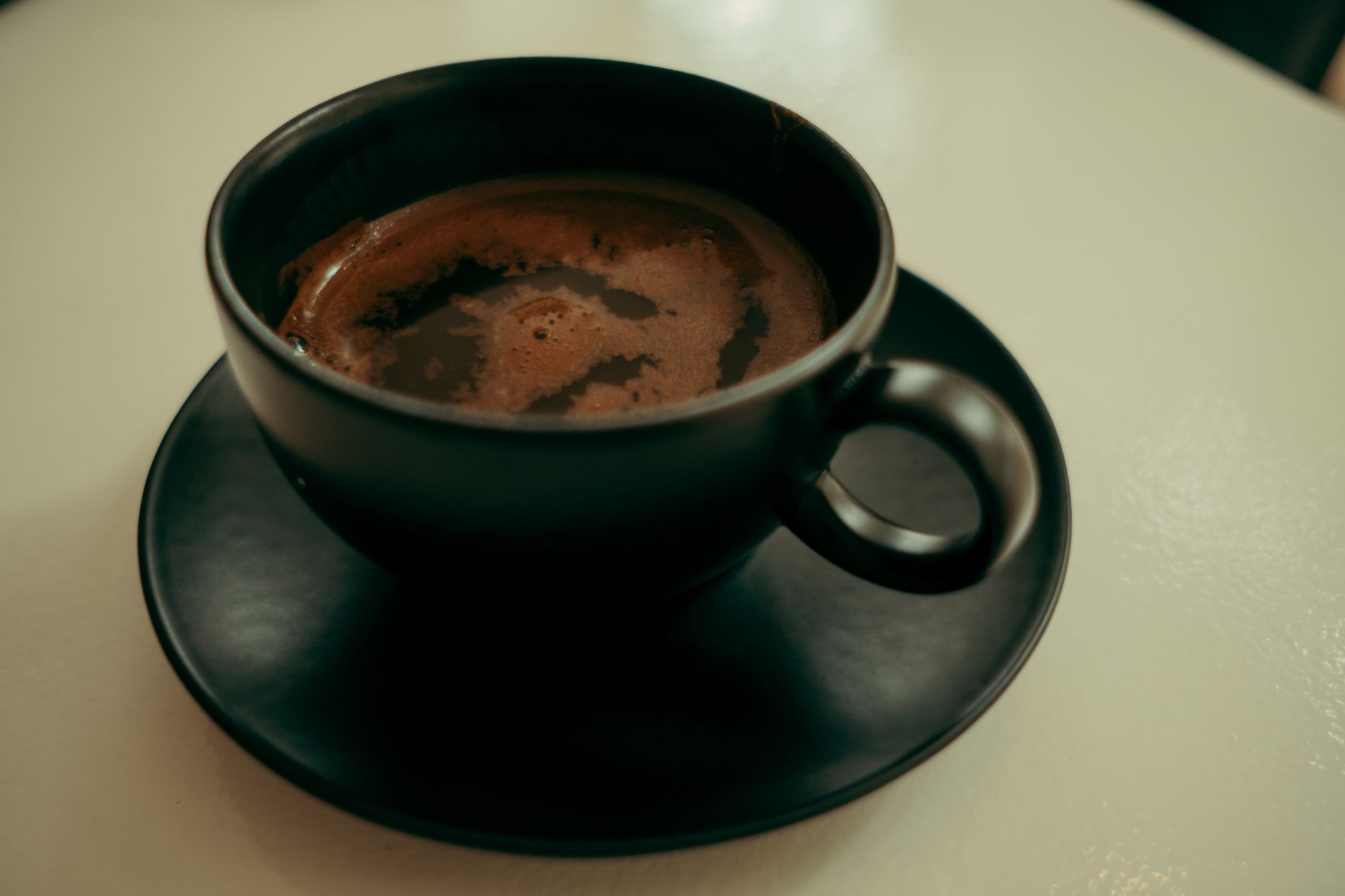 A cup of black coffee on a saucer, one of the common causes of surface staining on teeth.